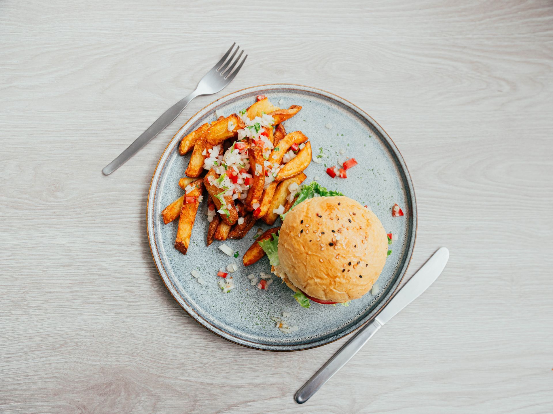 A plate of food with a hamburger and french fries on a table.