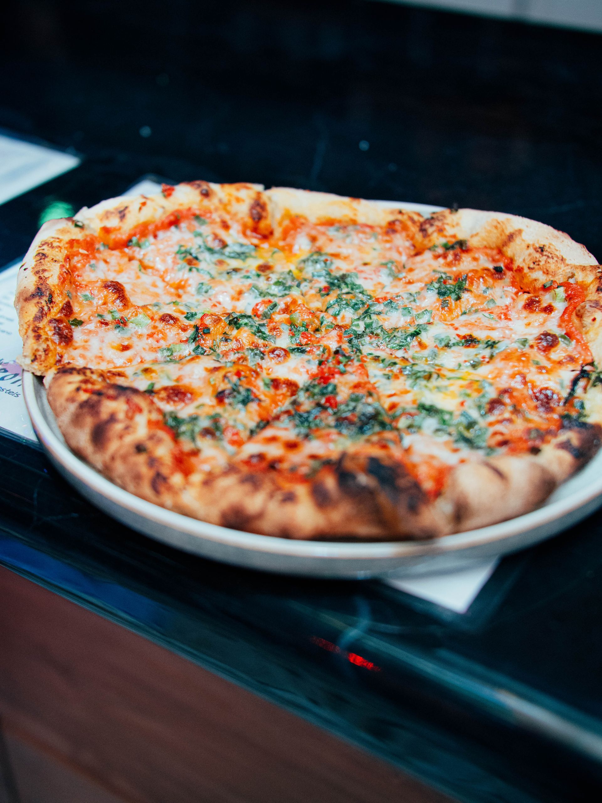 A pizza is sitting on a white plate on a table.