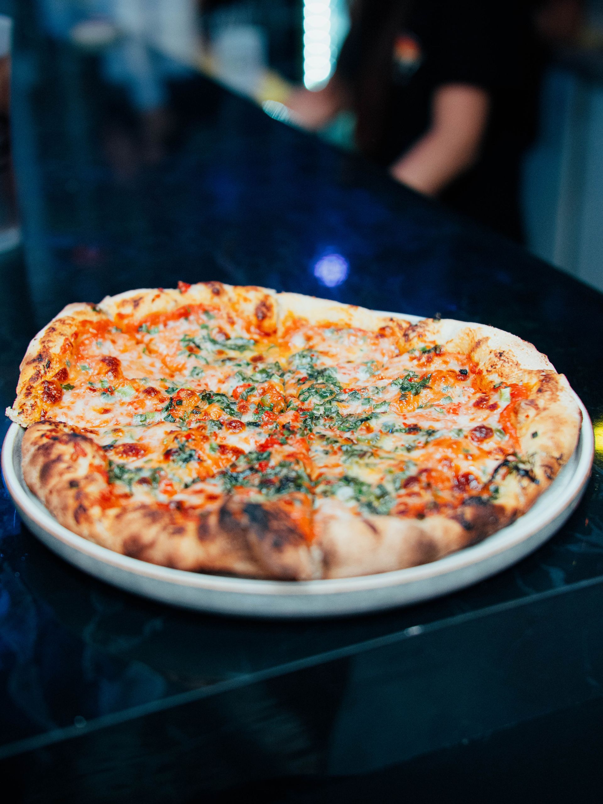A pizza is sitting on a white plate on a table.
