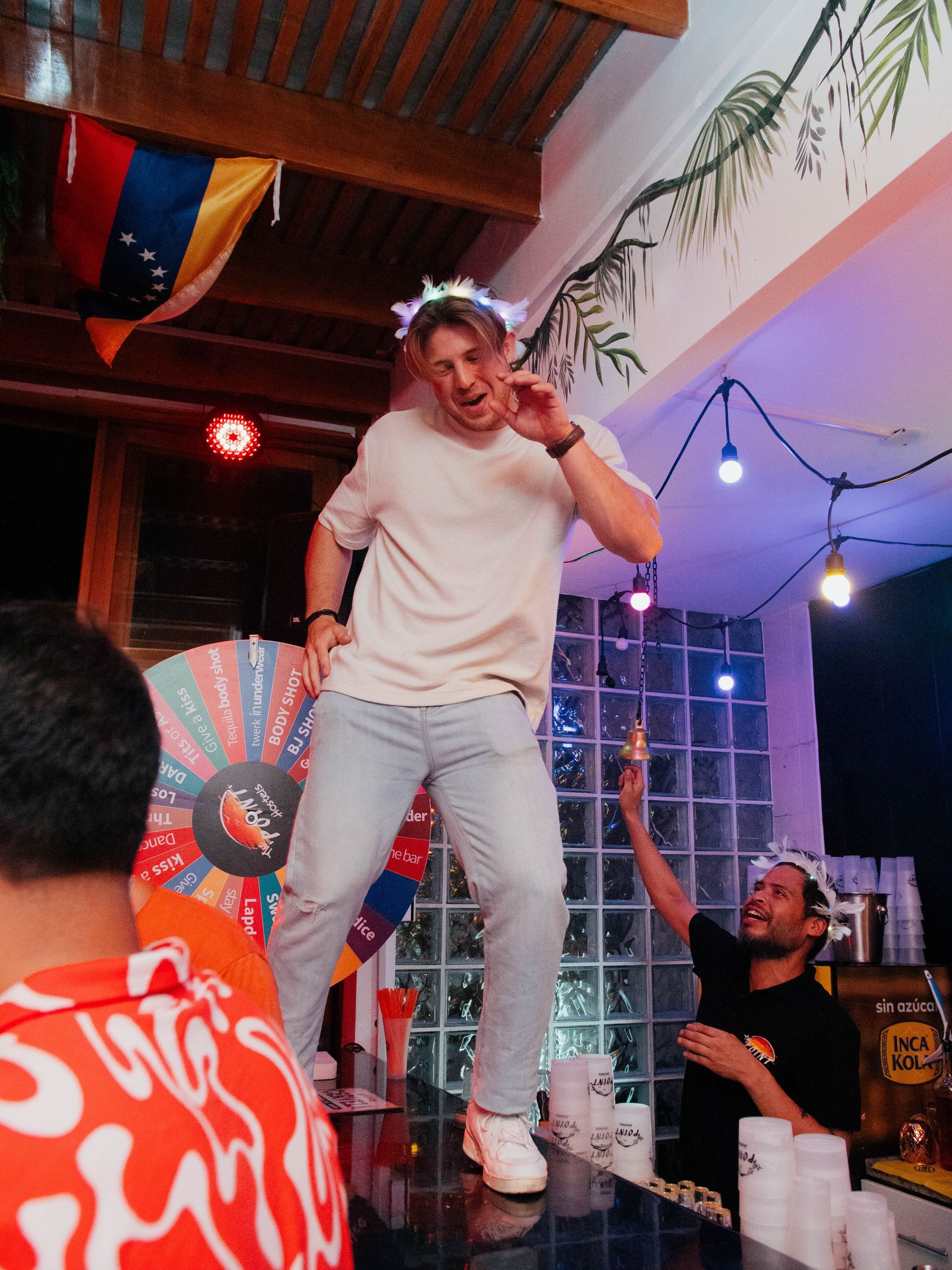 A man in a white shirt is dancing in a room with other people