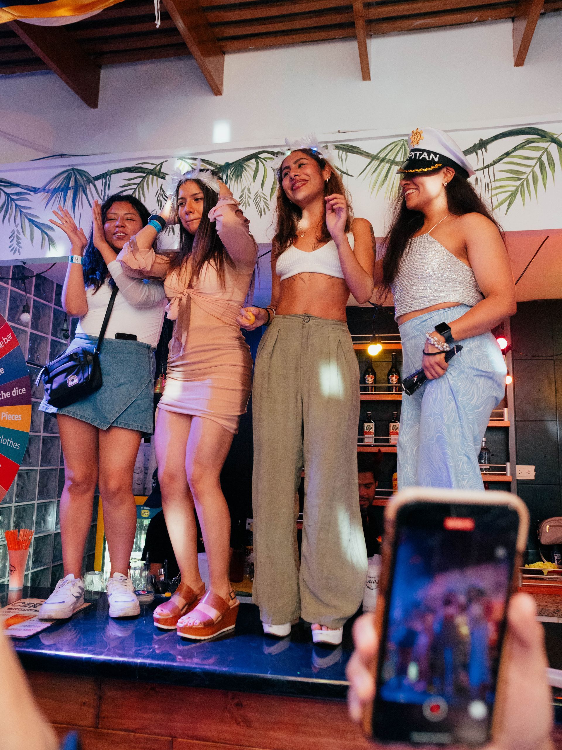 A group of women are standing on a stage and a person is taking a picture of them.