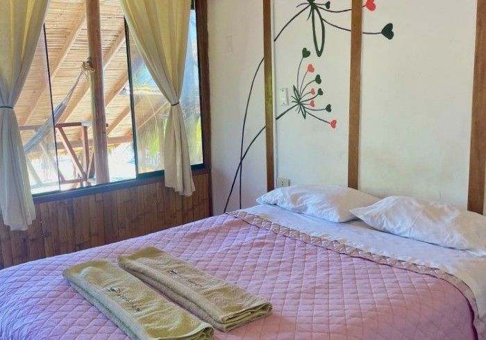 A bedroom with a bed and a window with a painting on the wall.
