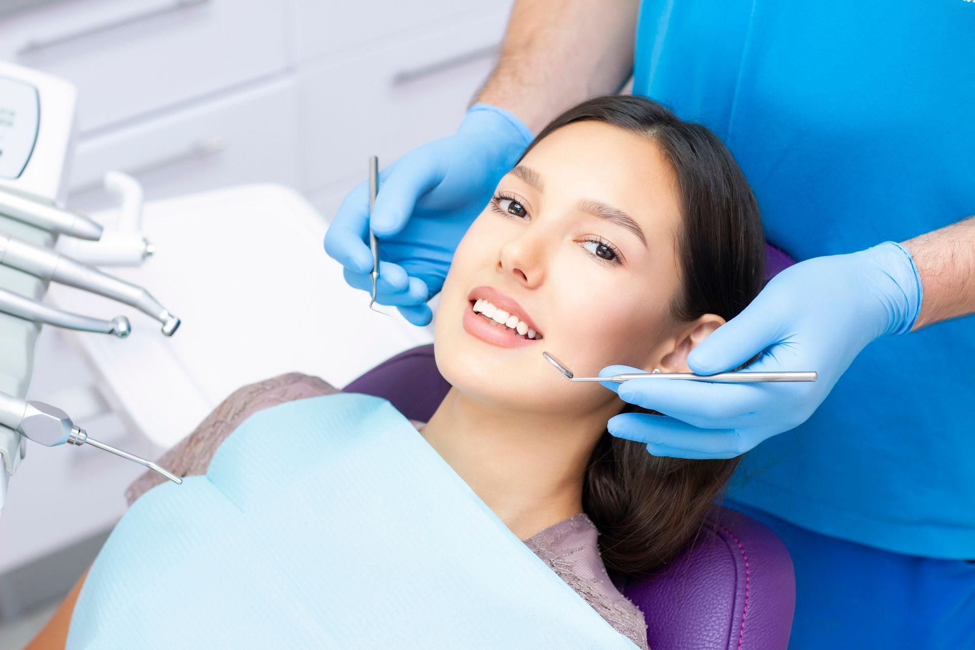 Woman in dentist chair with dentist performing a checkup.