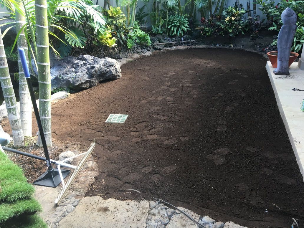 A shovel for grading is sitting on top of a pile of dirt in a garden.