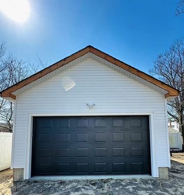 White garage with a black double door under a bright blue sky