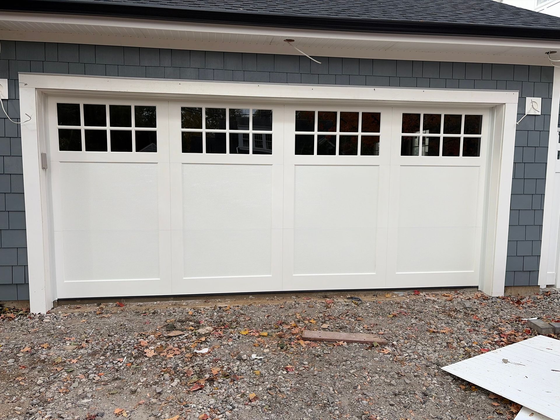 Open garage with raised door, ceiling opener, and view of driveway and trees outside