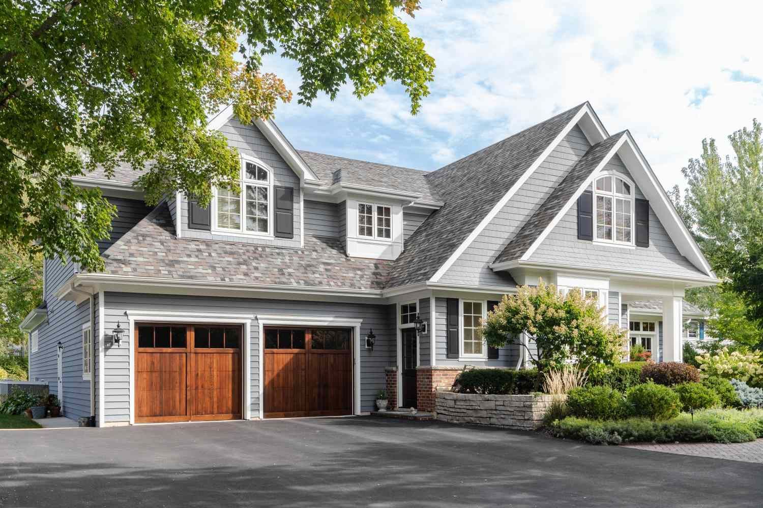 Gray two-story house with white double garage doors at dusk