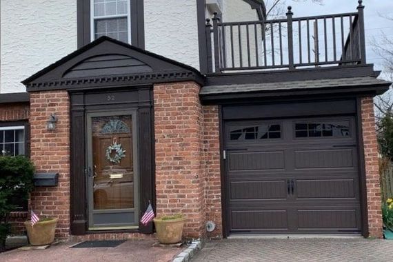White garage with a black double door under a bright blue sky