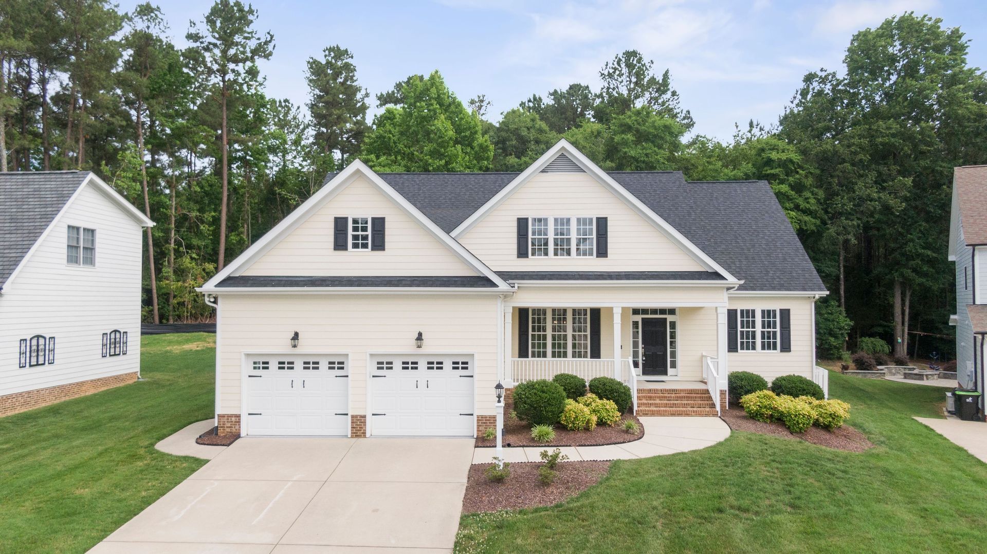 Gray two-story house with white double garage doors at dusk