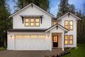 Modern two-story white house with lit windows, a garage, and a front porch at dusk