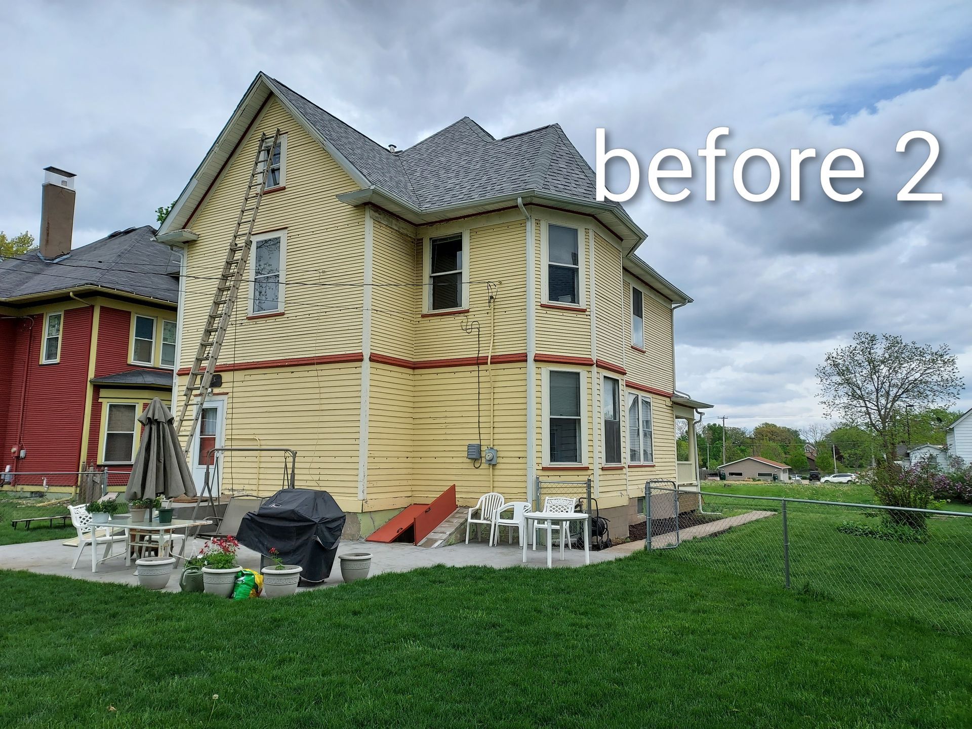 Yellow house with damaged siding and workers’ tools in the yard, labeled “before 2”