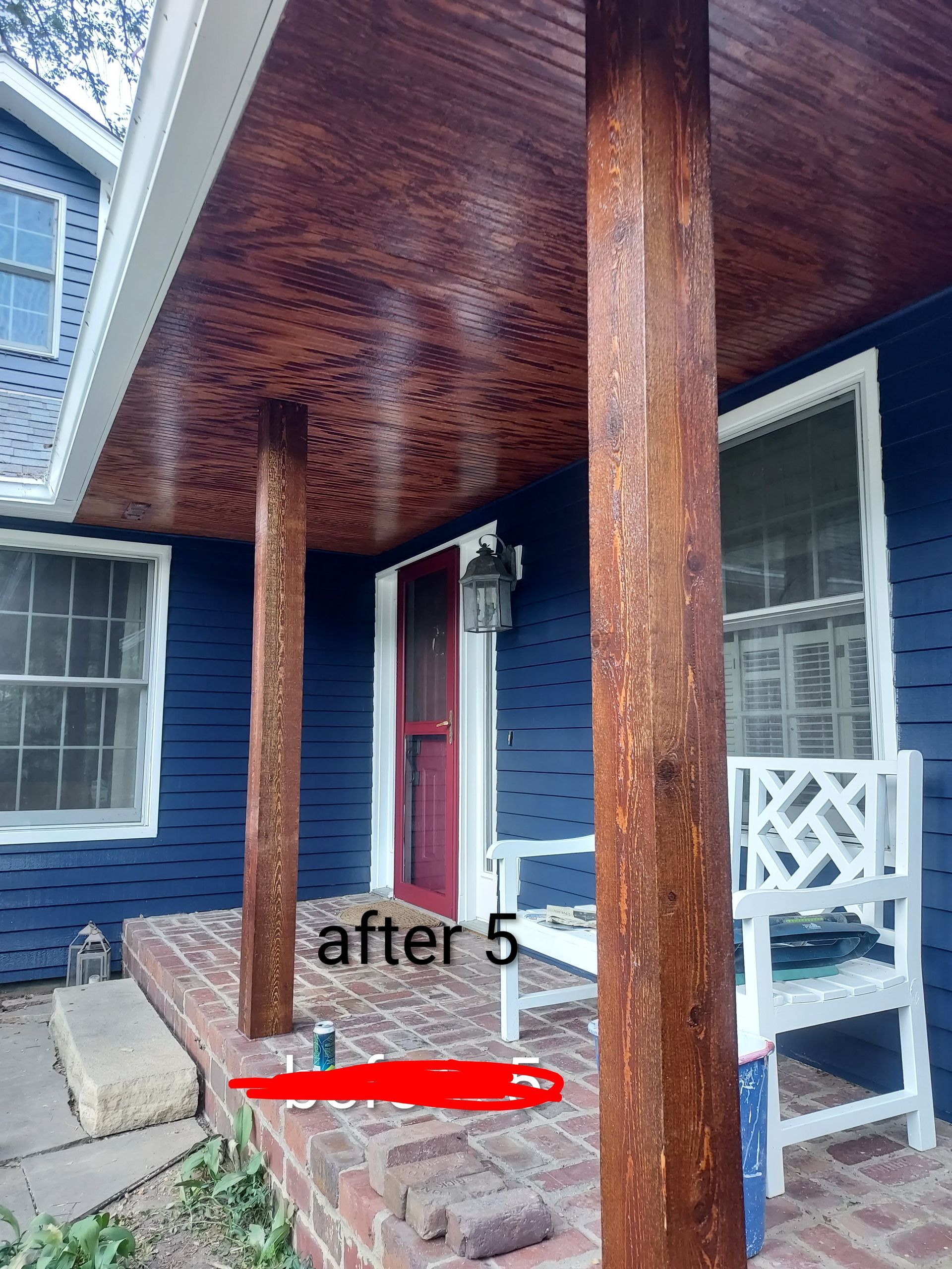 Front porch with dark wood columns, blue house exterior, white chair, and red arrow marking the floor area.