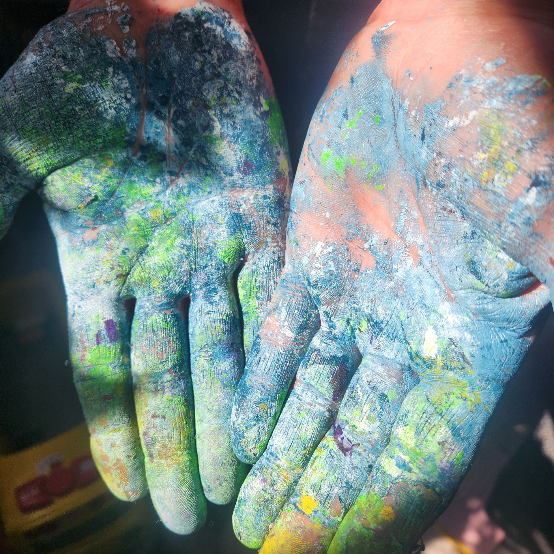 Hands covered in colorful powder paint, palms open and facing up.