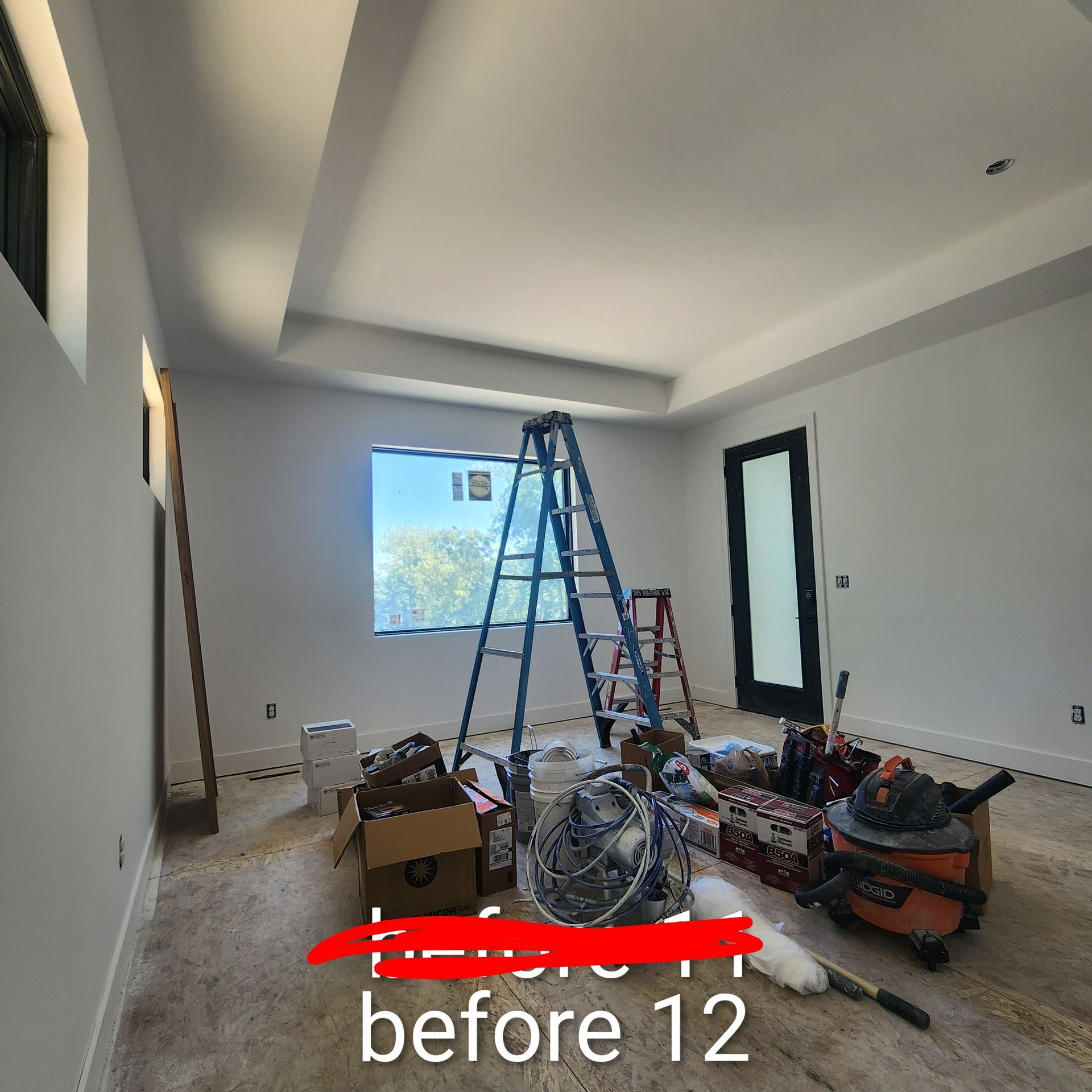 Unfinished room with ladders, tools, and construction materials on the floor near a window.