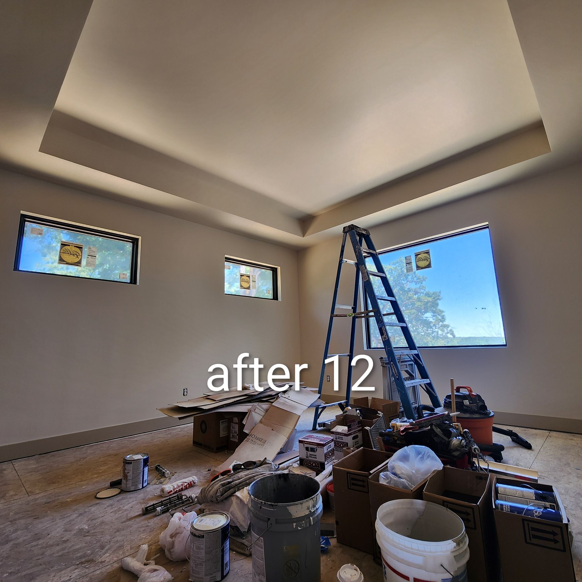 Partially renovated room with blue ladder, tools, and materials on the floor under skylight windows