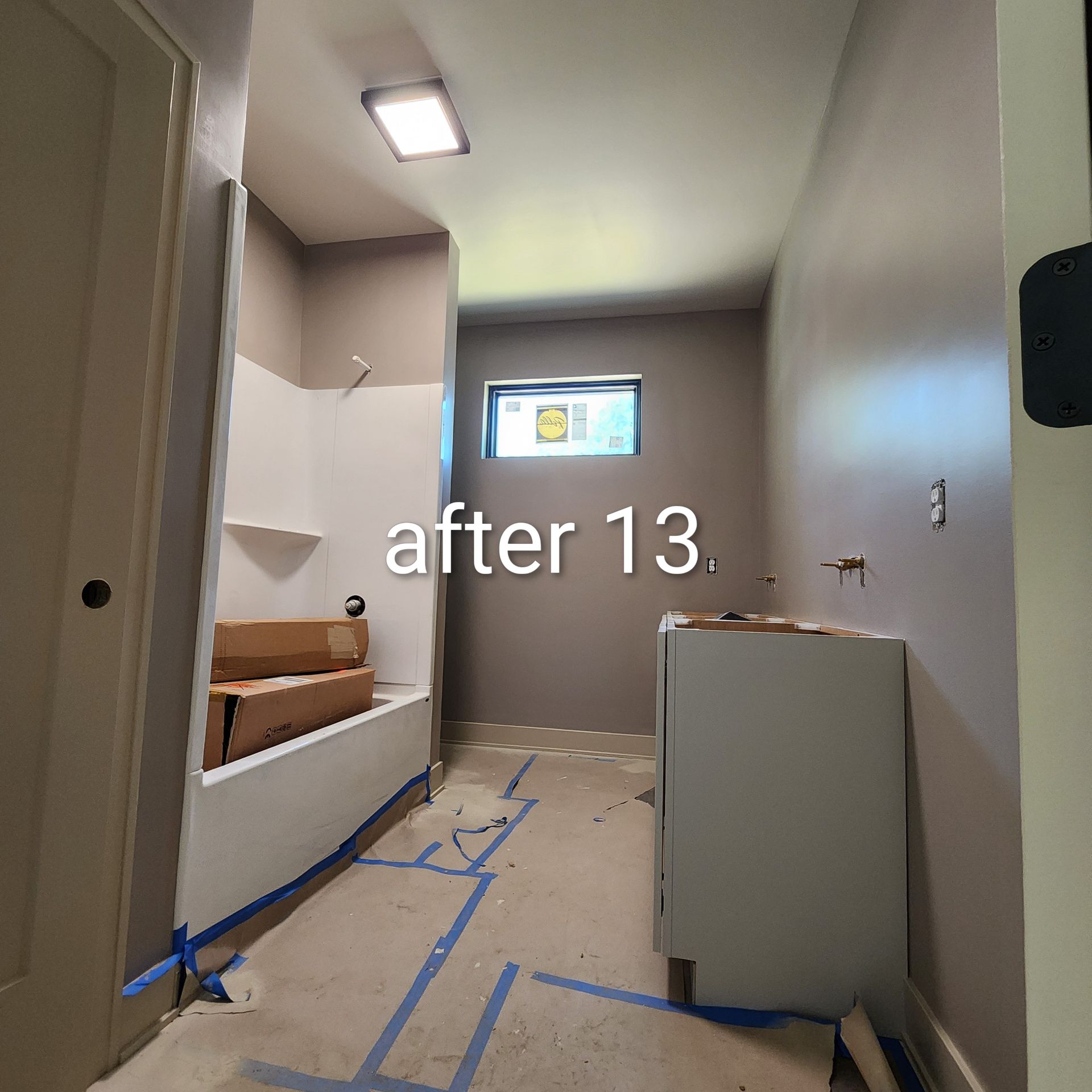 Bathroom under renovation with taped floor, sink cabinet, and a small window labeled “after 13.”