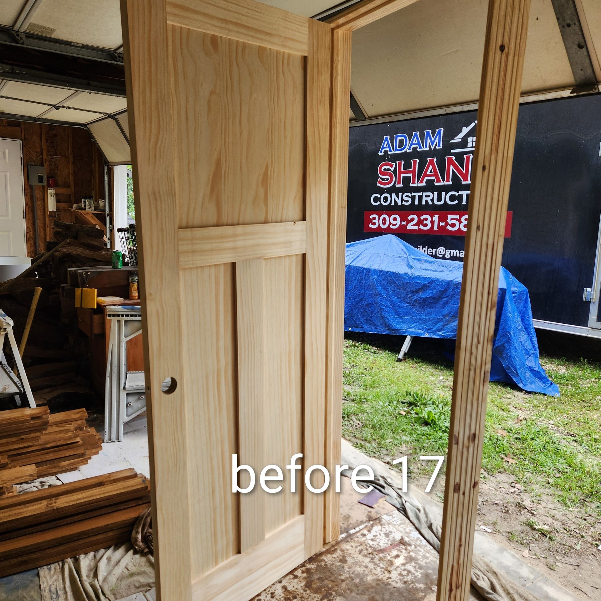 Wooden door frame under construction inside a workshop, with a partially installed door panel.