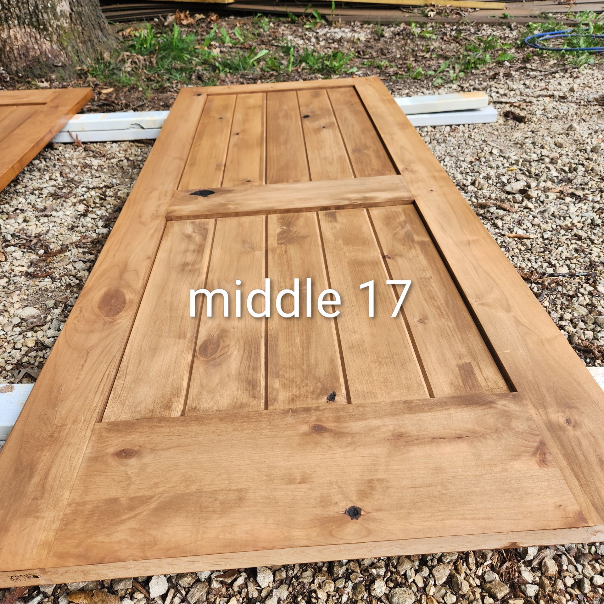 Wooden door panel on gravel, marked “middle 17,” with boards and metal hinges visible.