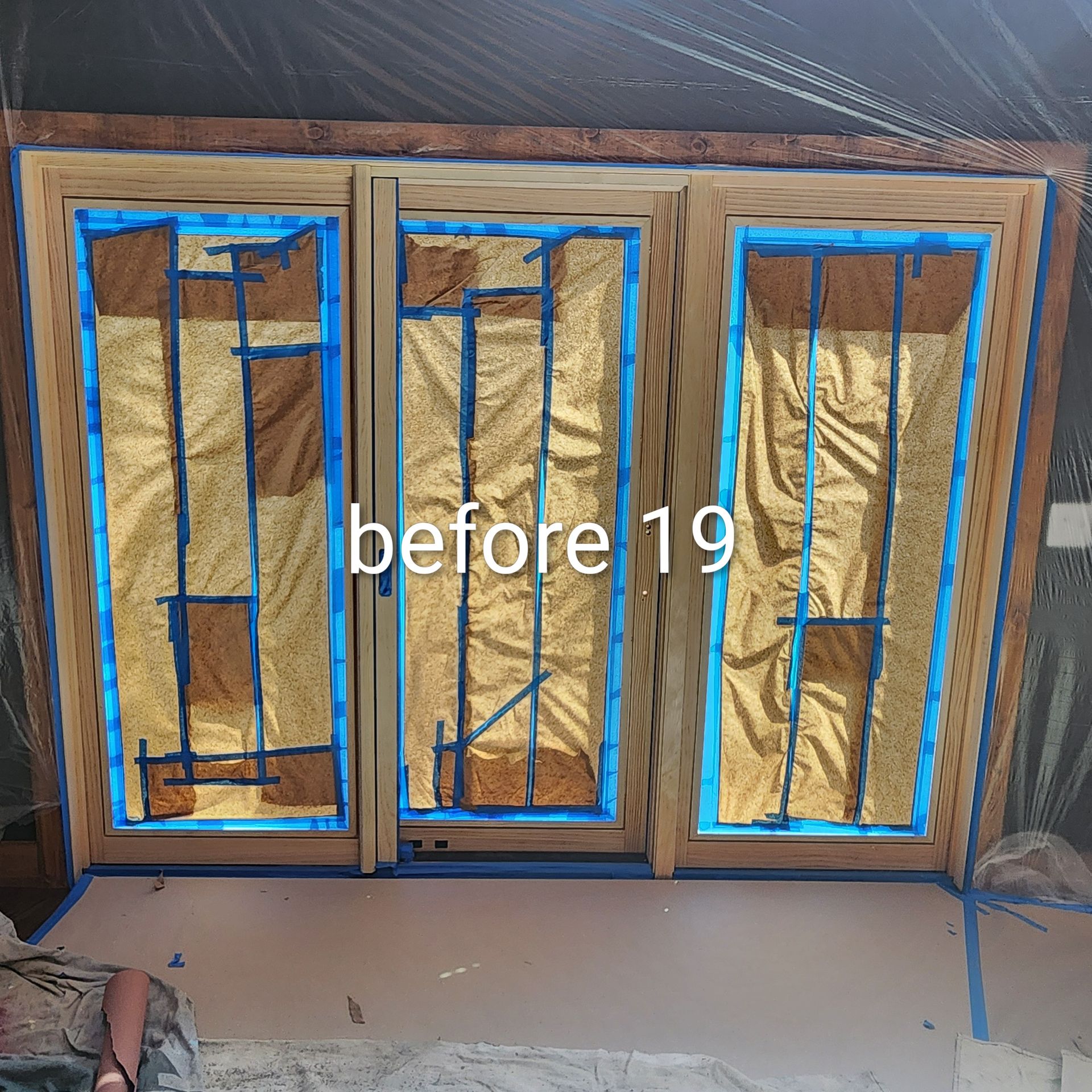 Three window frames taped off with blue painter’s tape over tan sheeting, labeled “before 19.”
