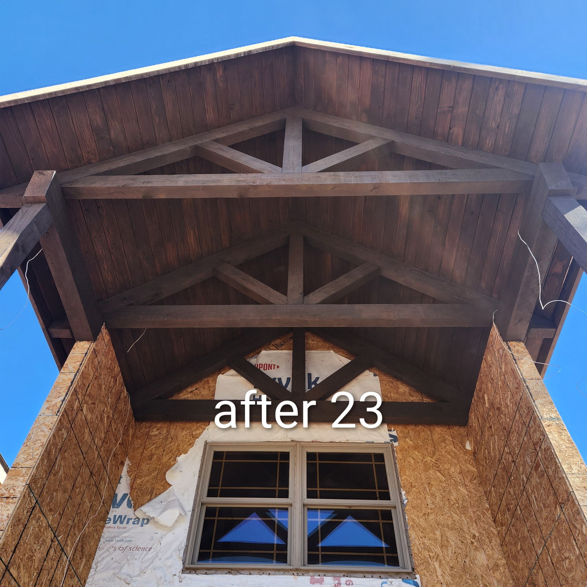 Upward view of a wooden balcony roof and window on a brick building, with “after 23” text overlaid