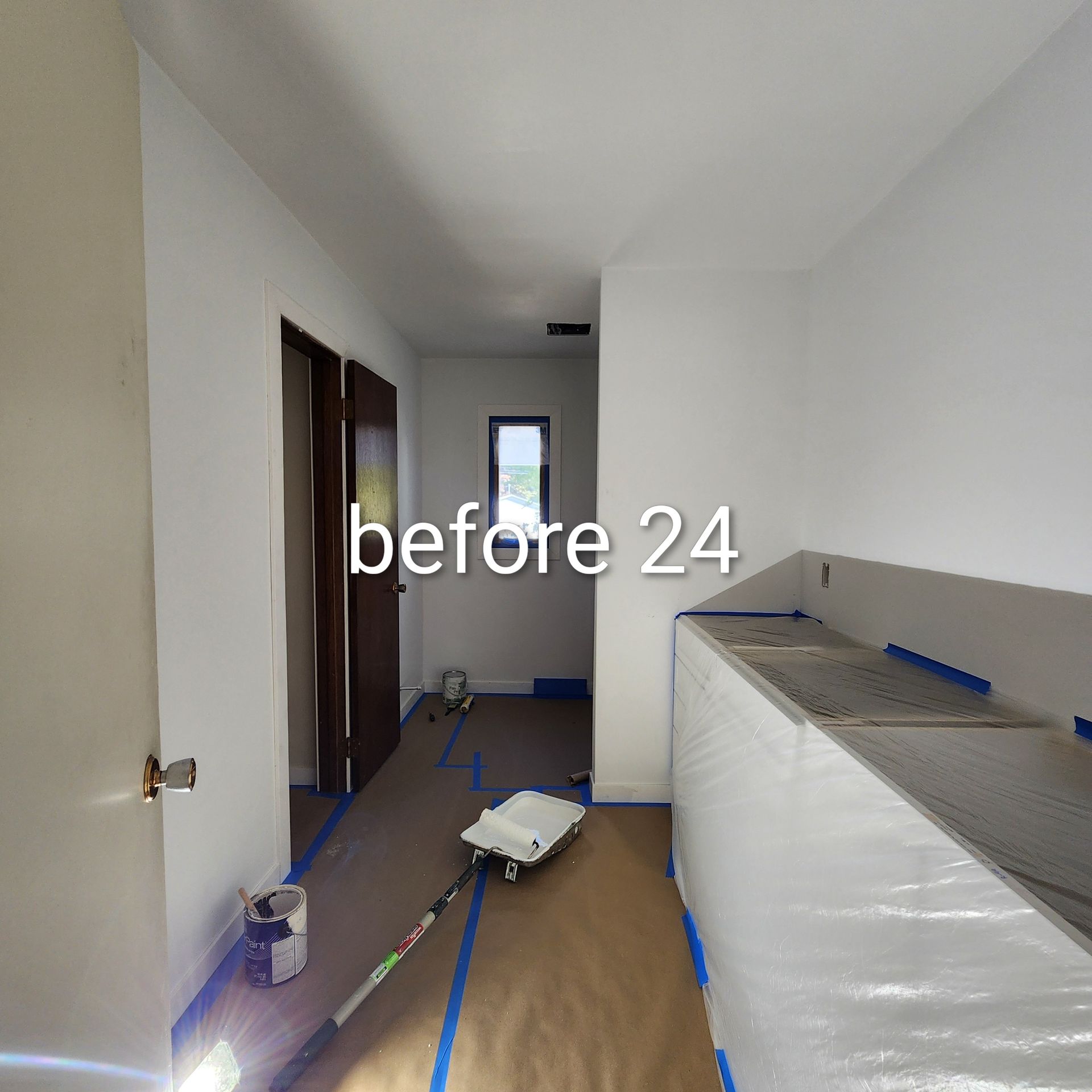 Narrow hallway under renovation with tools, paint cans, and a large wrapped countertop or cabinet on the right.