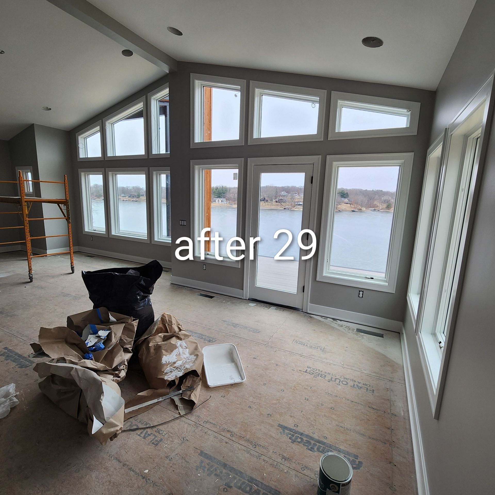 Unfinished room with floor debris, large windows, and a lake view through glass doors.