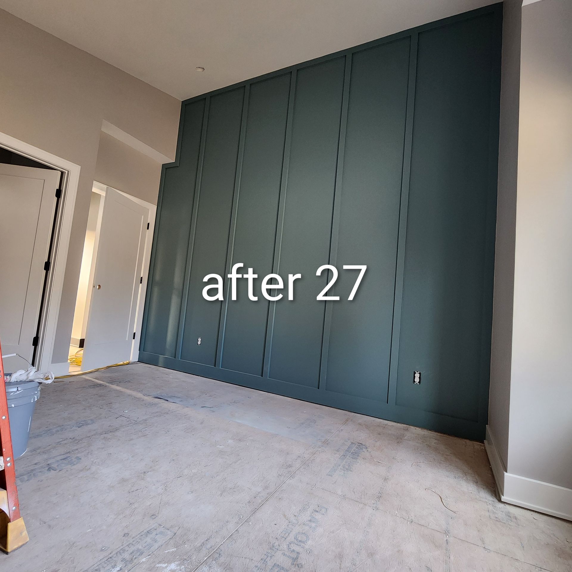 Empty room with a tall dark green paneled accent wall and unfinished floor, labeled “after 27”