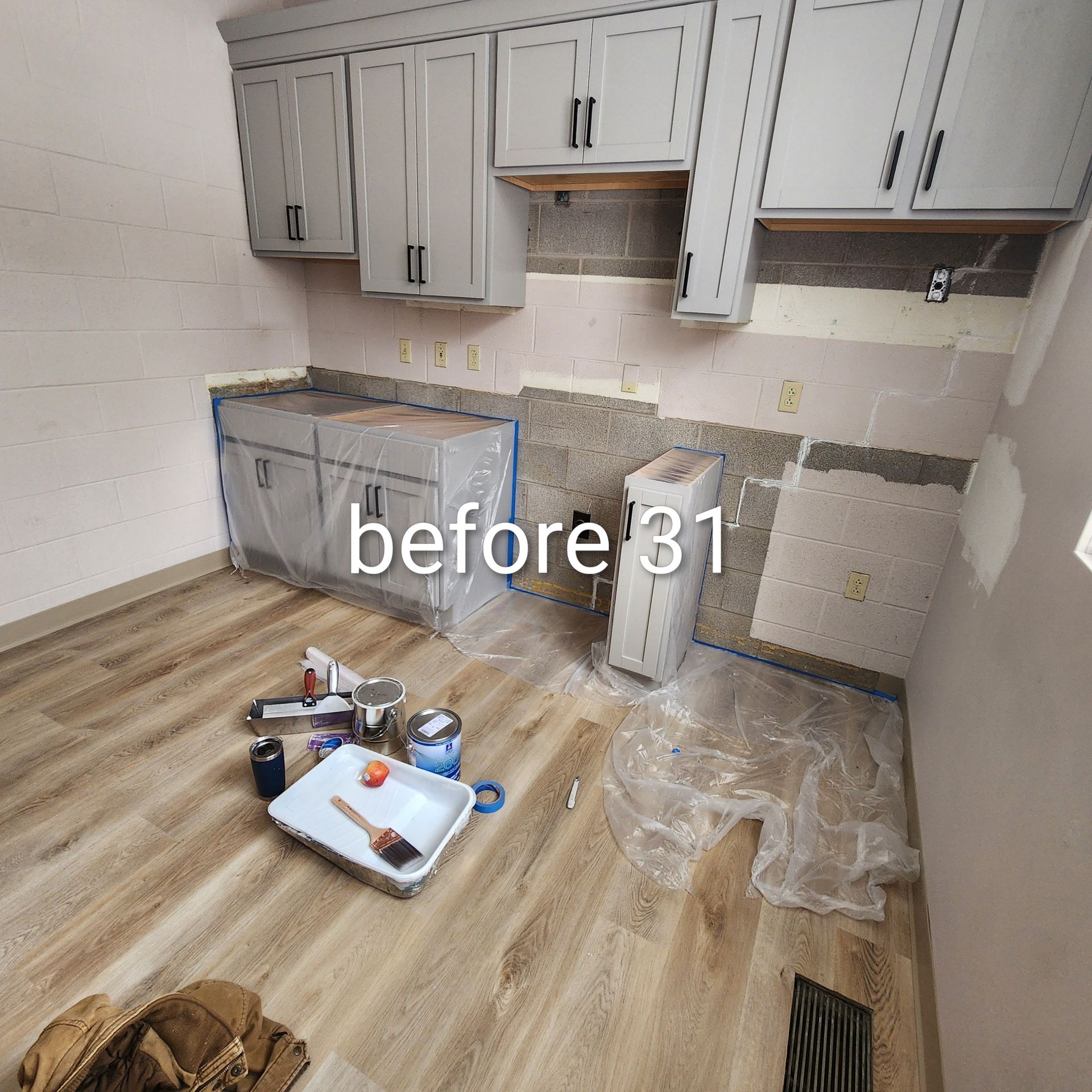 Kitchen under renovation with white cabinets, granite countertops, and tools on the floor