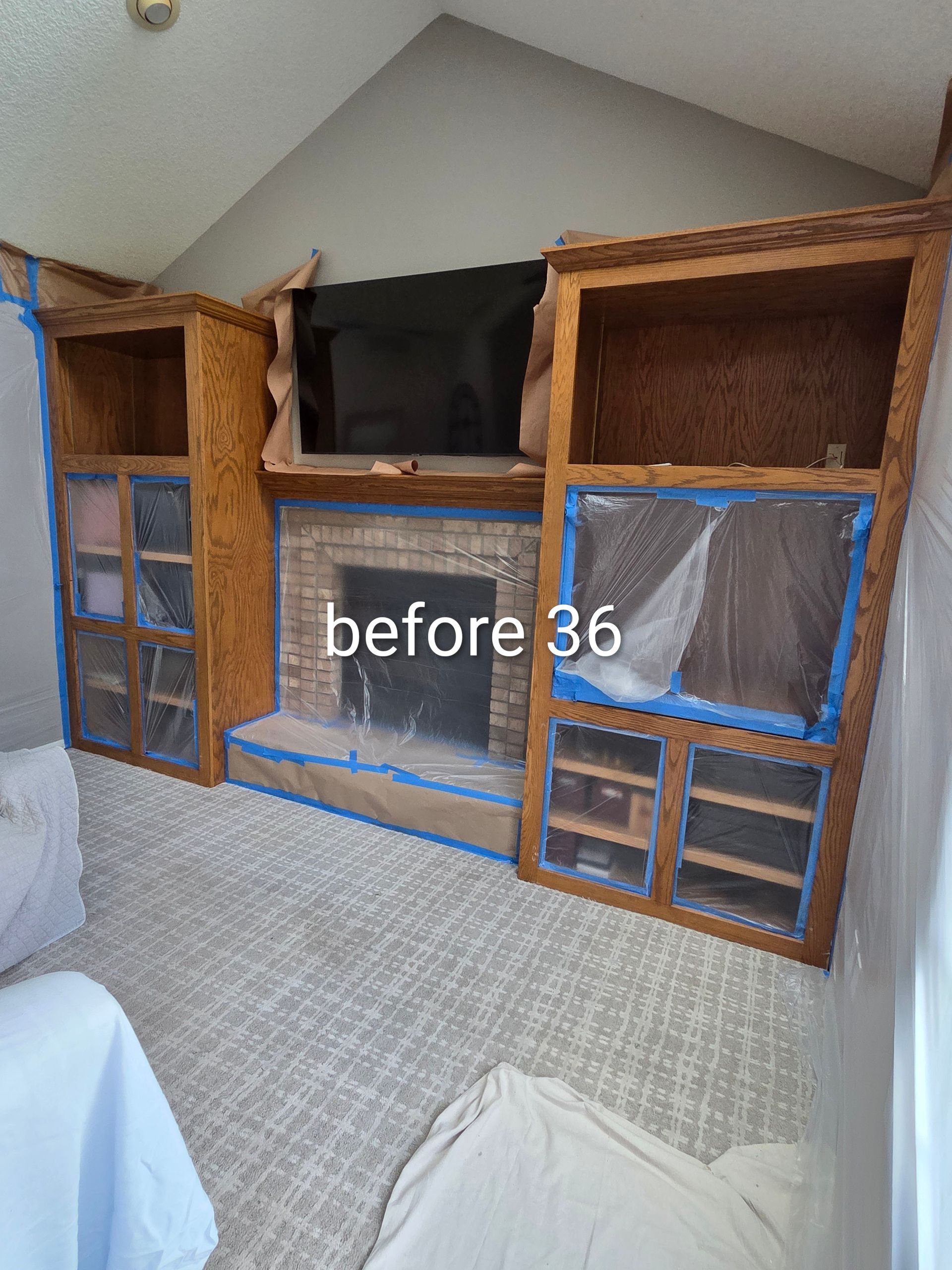 Wooden built-in cabinets and shelves in a slanted room, with blue tape marking sections before renovation