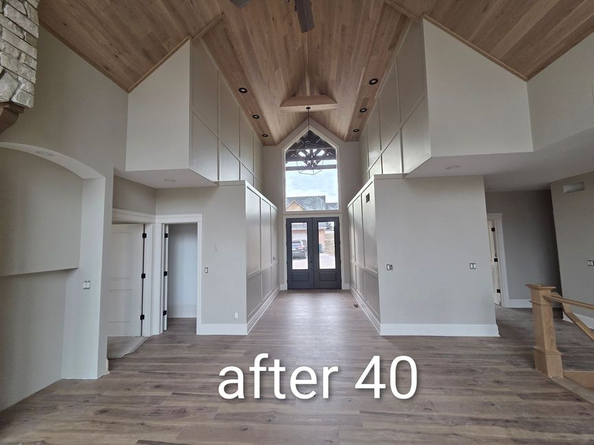 Empty renovated room with vaulted wood ceiling, white walls, gray floors, and double doors at the far end