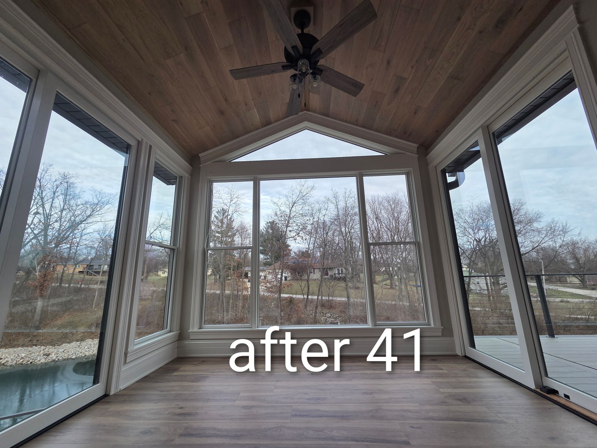 Sunroom with wood-paneled ceiling, ceiling fan, and glass walls overlooking a yard; text says “after 41”