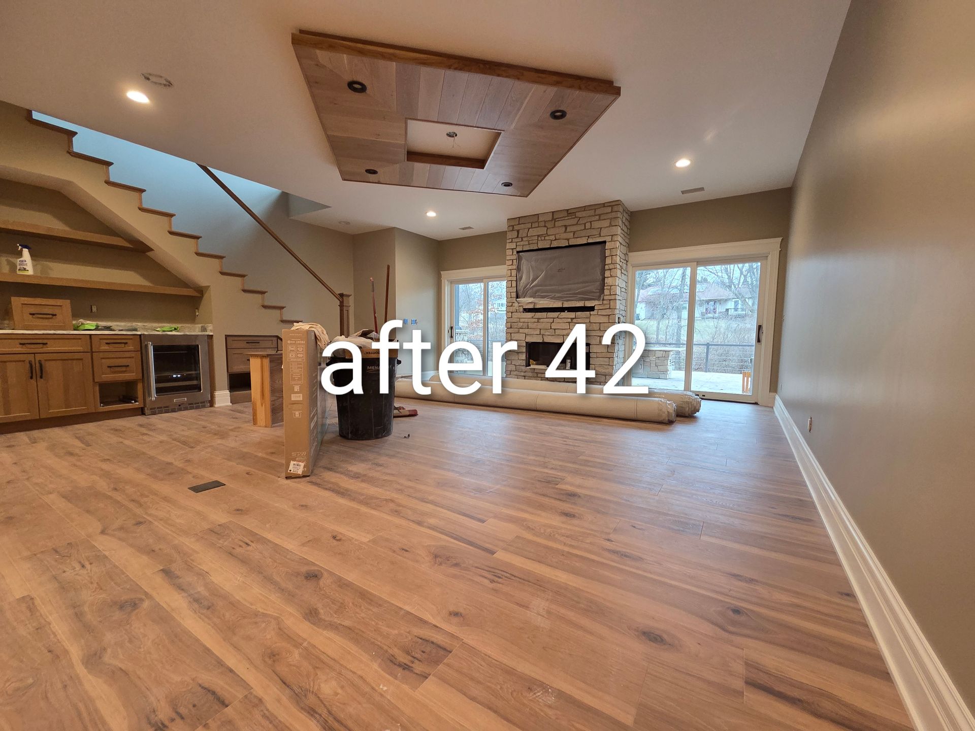 Empty renovated living room with wood floors, staircase, and stone fireplace; text overlay reads “after 42”