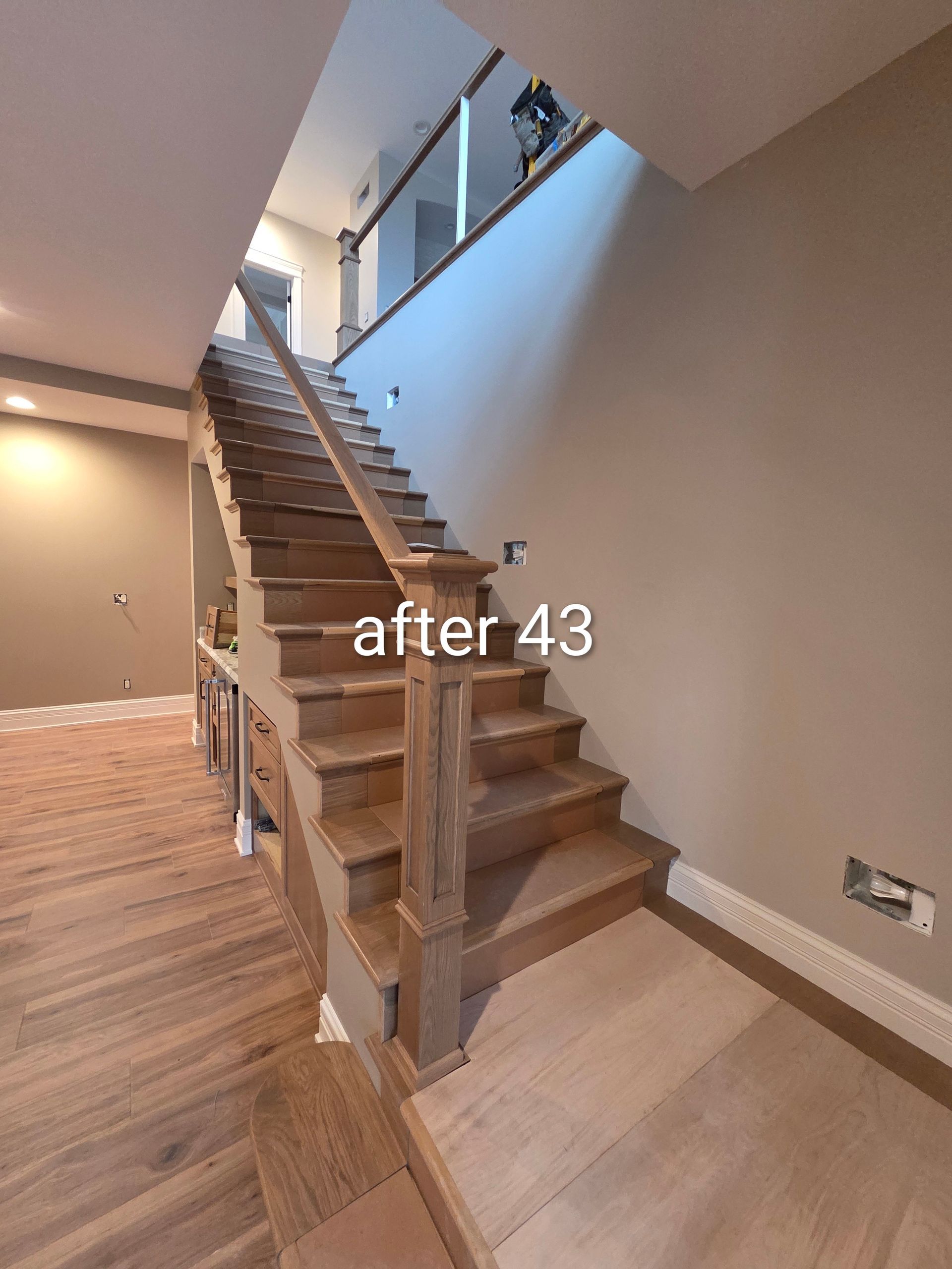 Interior staircase with wood treads, white railing, and beige walls in a modern home.