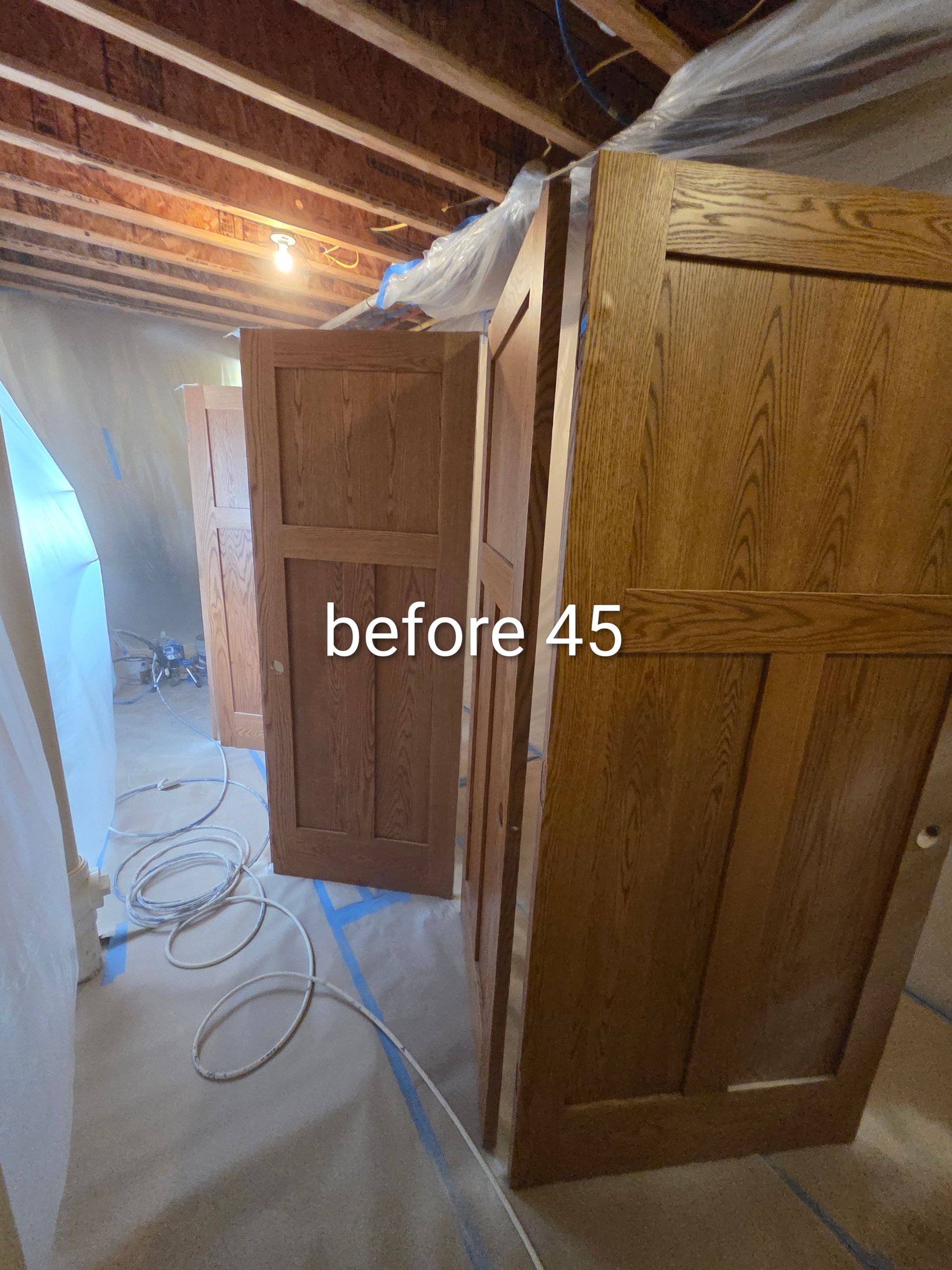 Basement with several wooden doors leaning against a wall and coiled cables on the floor.
