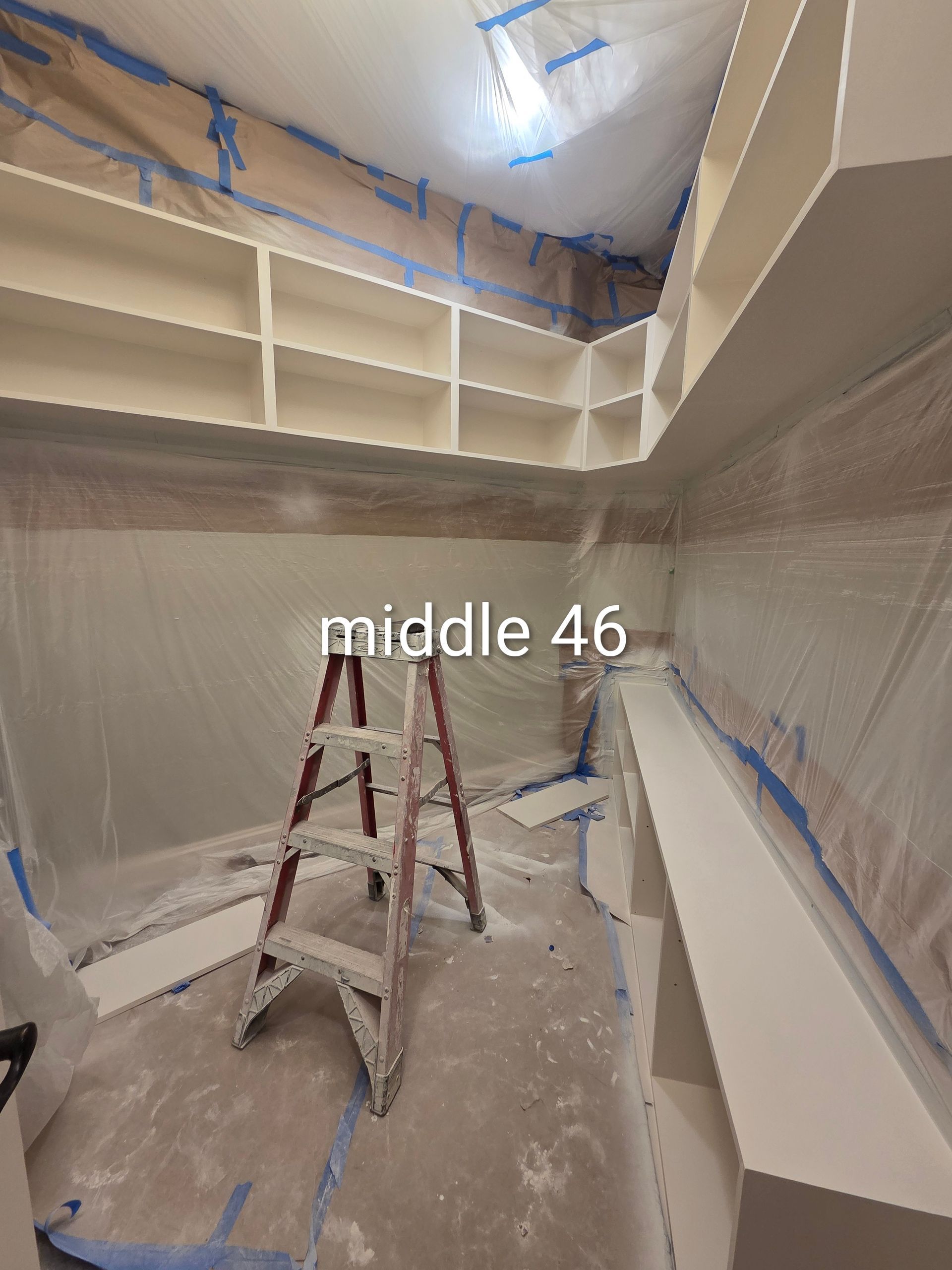 Partially finished room with drywall, blue tape, and a ladder under a ceiling cutout
