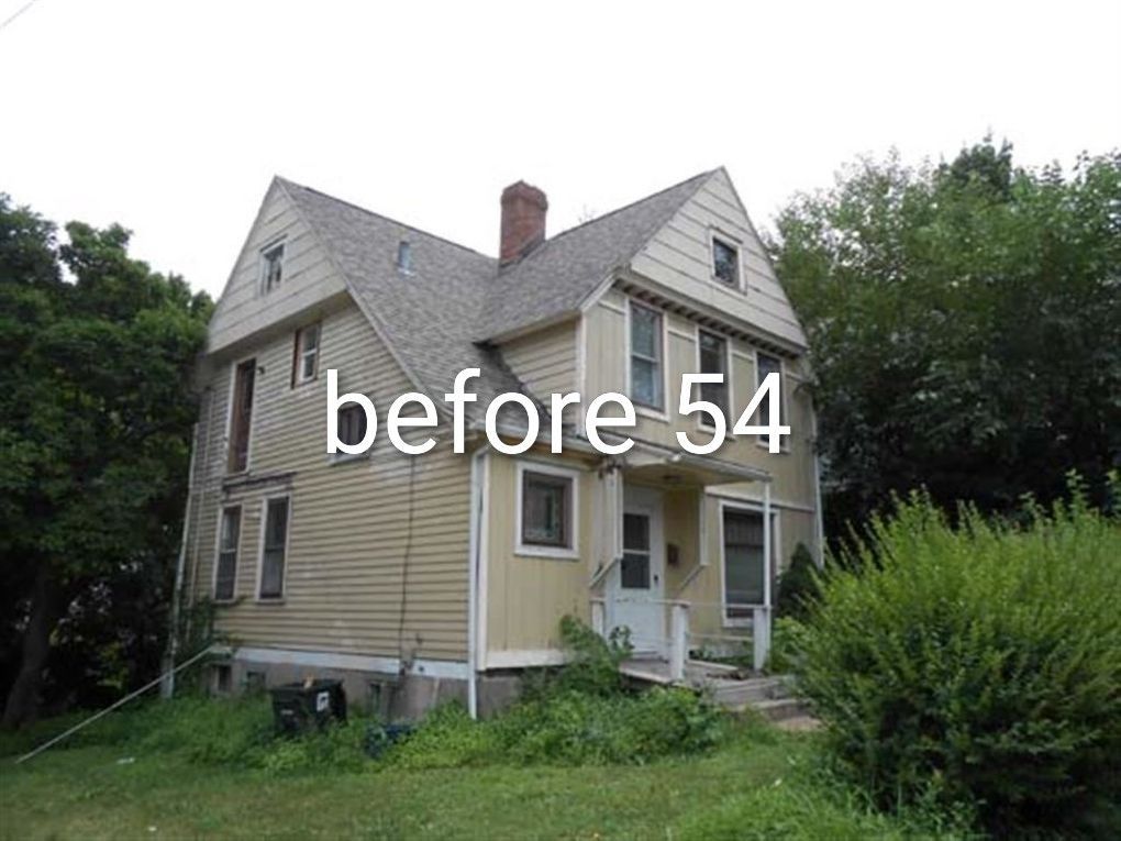 Small beige house with a front porch, overgrown yard, and trees, labeled “before 54”