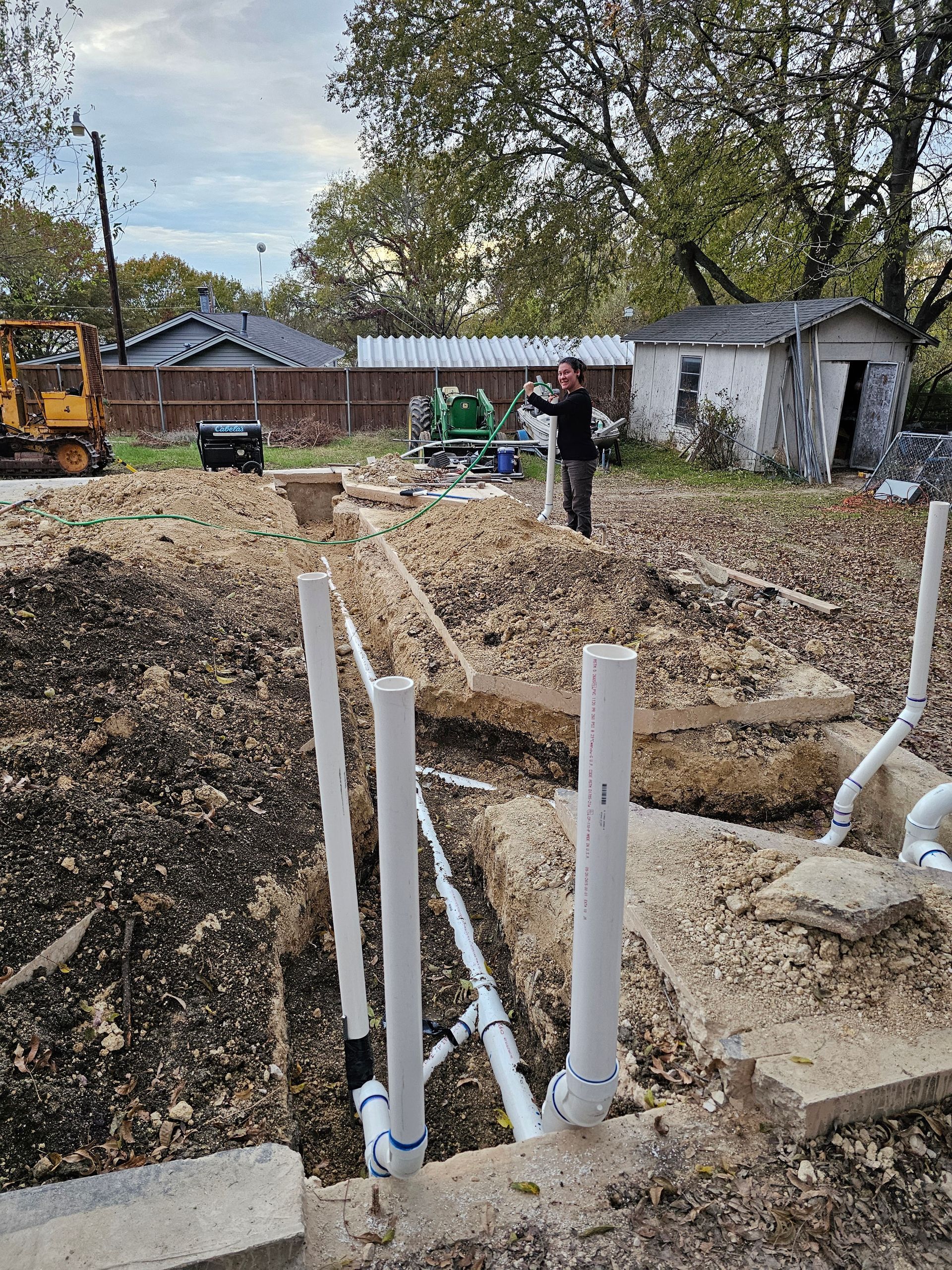 Construction site with white PVC pipes rising from trenches.