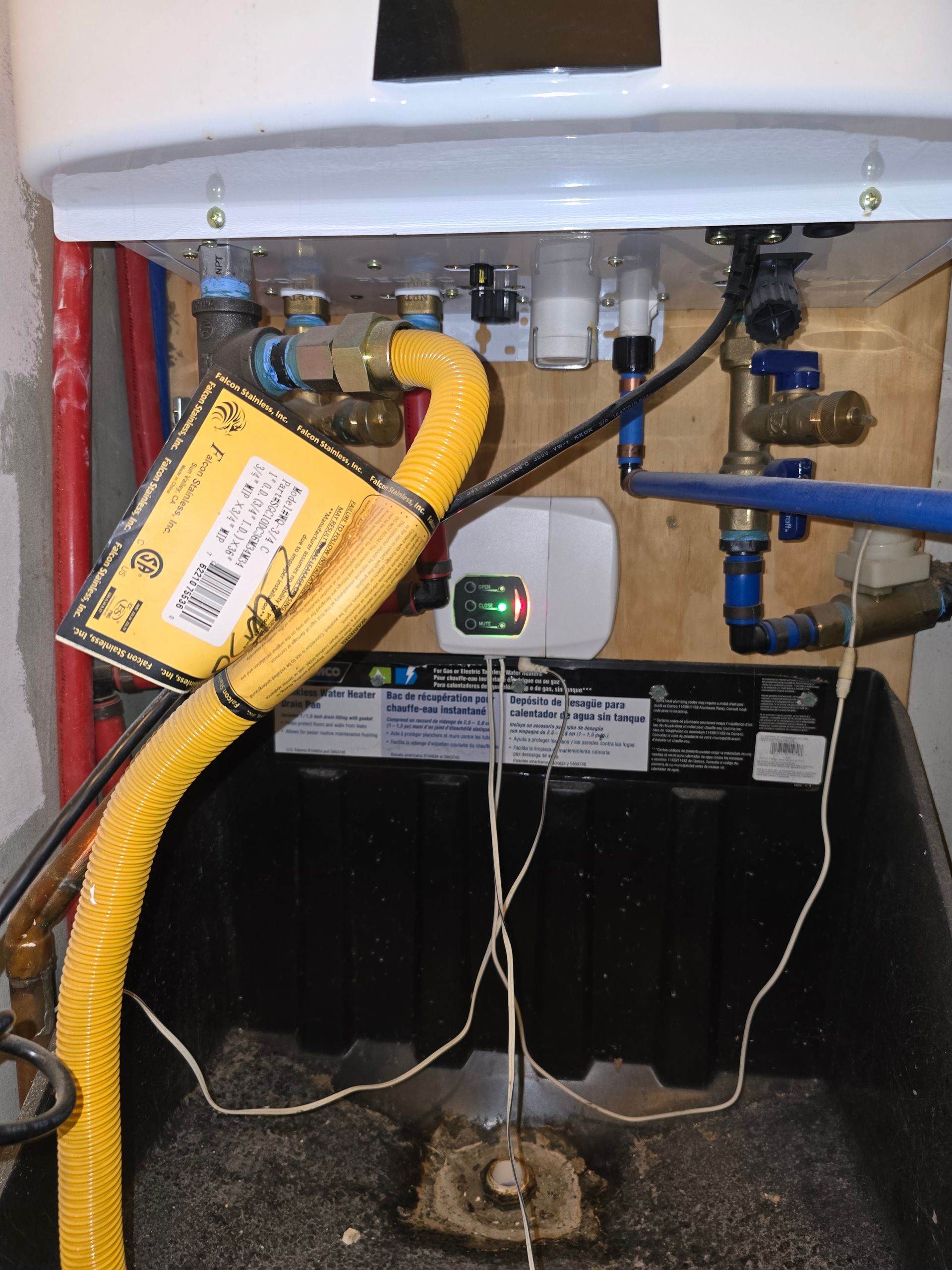 Water heater with yellow vent pipe, pipes, and electrical components.