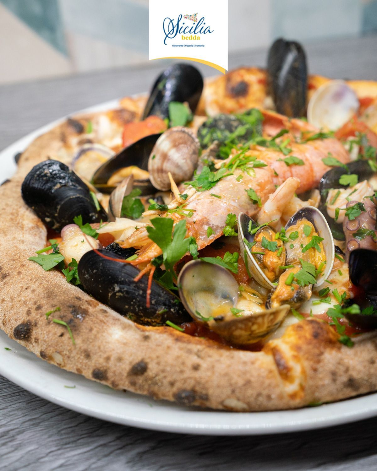 Pizza ai frutti di mare con cozze, vongole, gamberi e prezzemolo su un piatto bianco