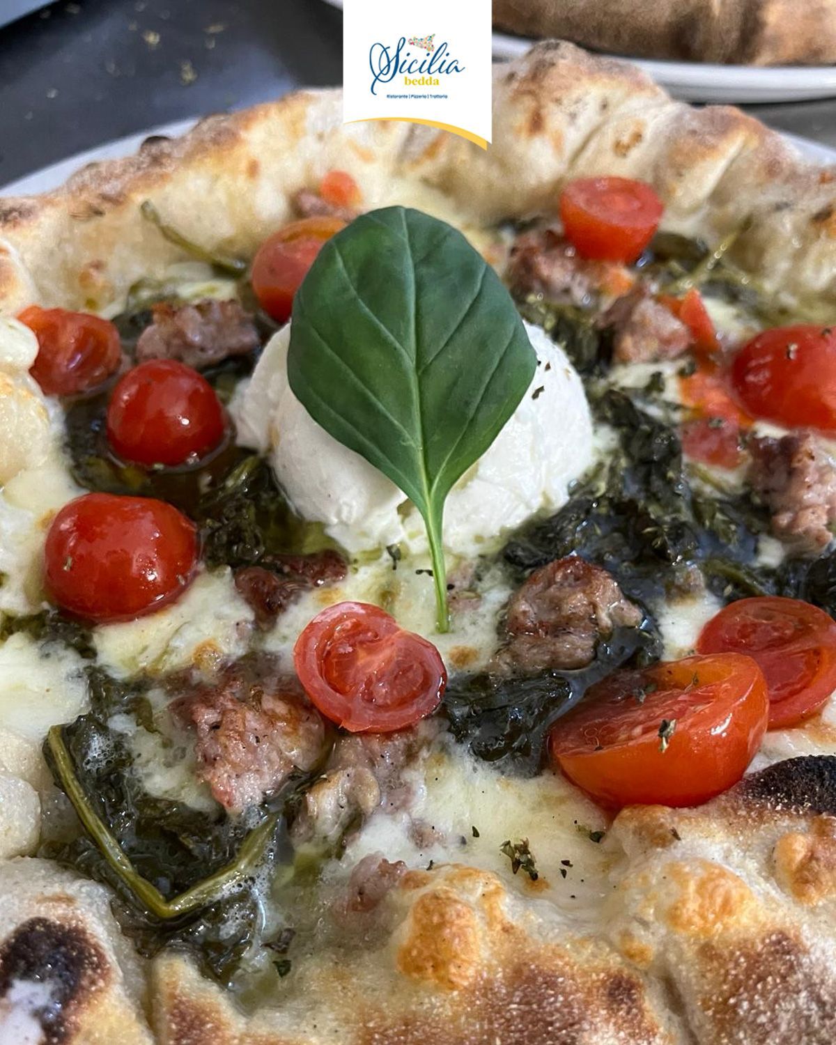 Pizza cotta nel forno a legna con pomodorini, verdure e basilico al centro.
