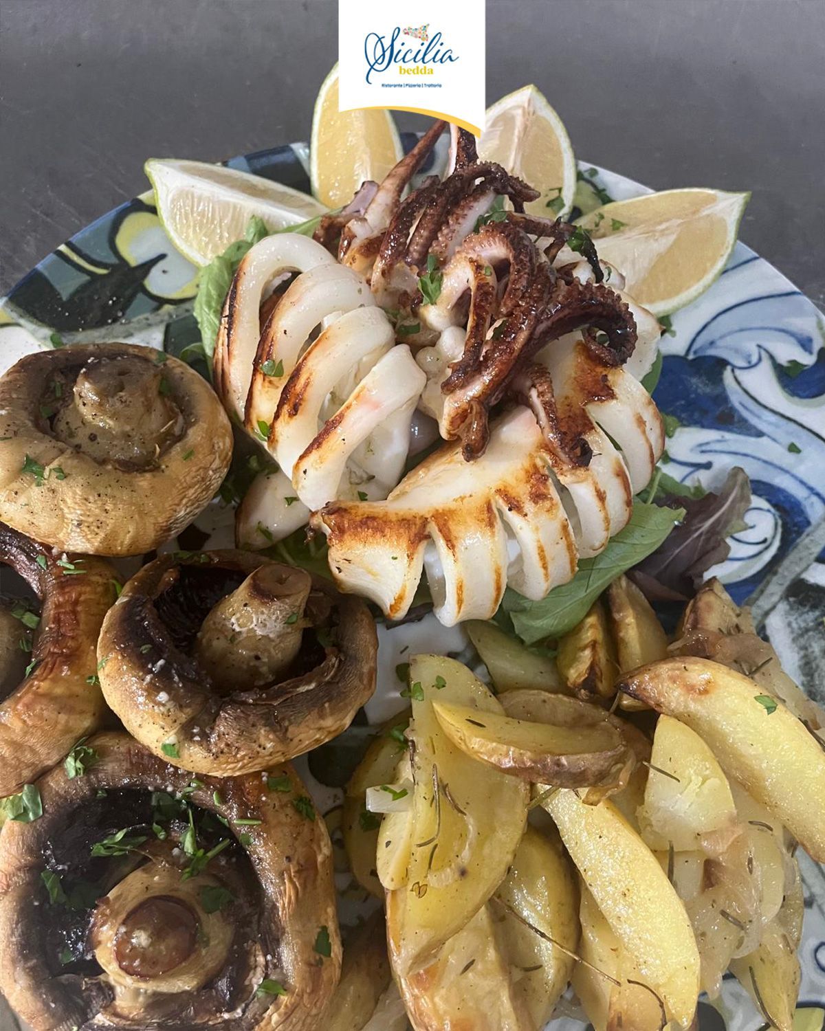 Piatto di frutti di mare grigliati con calamari, funghi, spicchi di limone e patate su un piatto decorato.