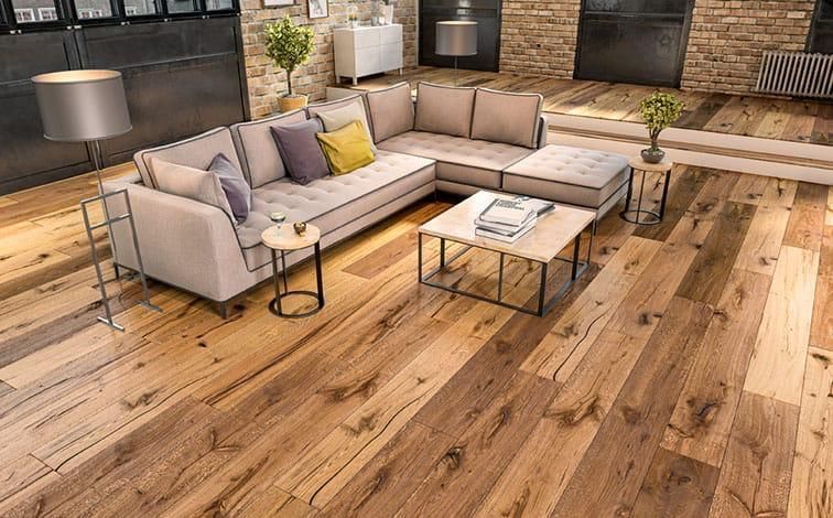 Wohnzimmer mit hellgrauem Ecksofa, Couchtisch aus Holz und Holzboden.