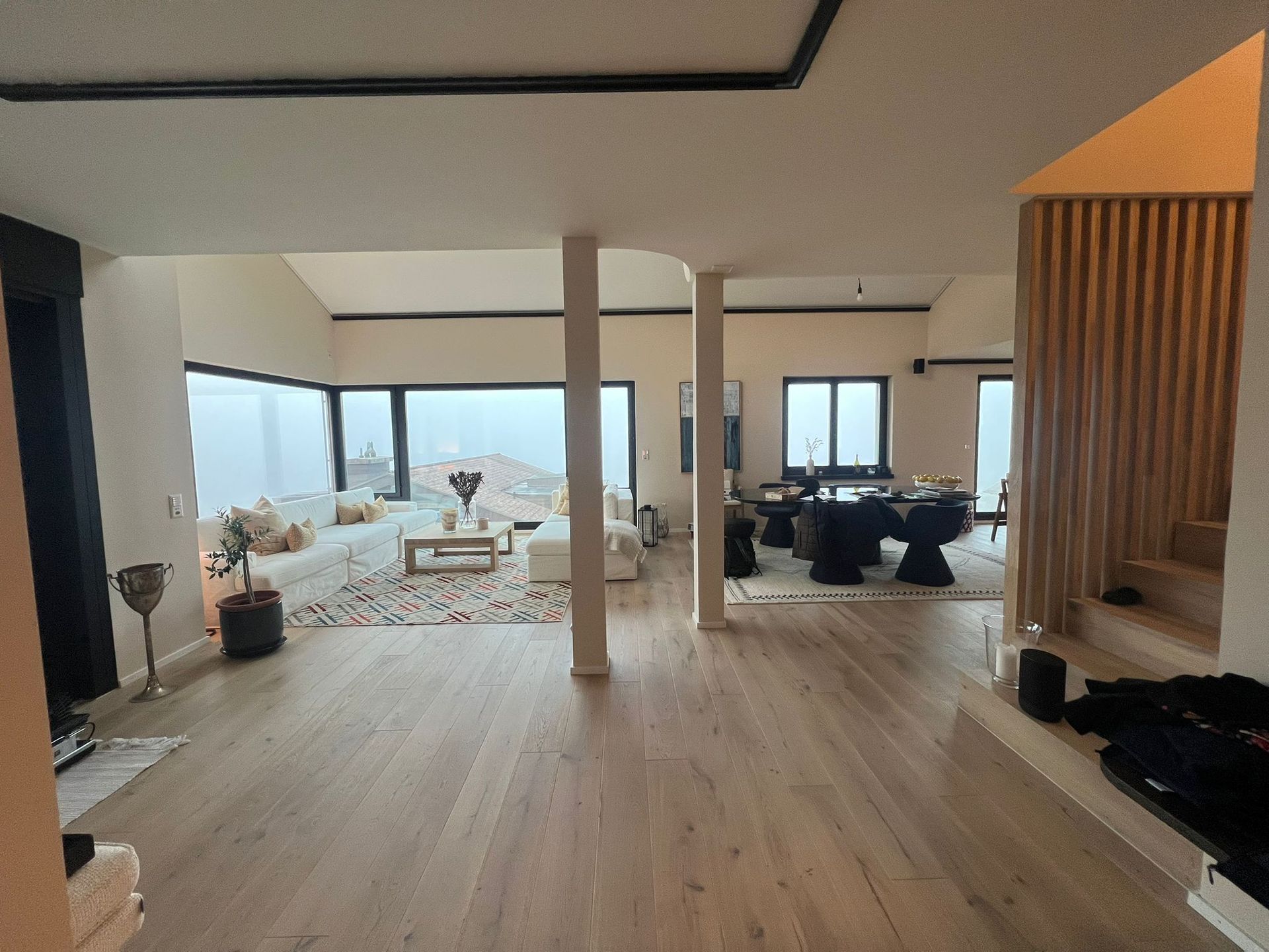 Großzügiger, moderner Wohnraum mit hellen Holzböden, Panoramafenstern und offenem Grundriss.