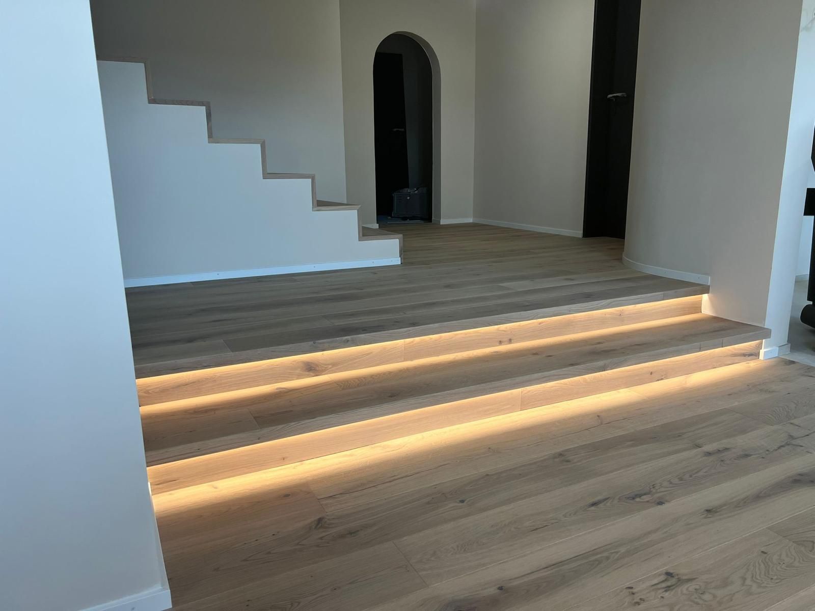Innenansicht: Holzboden mit von unten beleuchteten Stufen; Treppe, die nach oben führt.