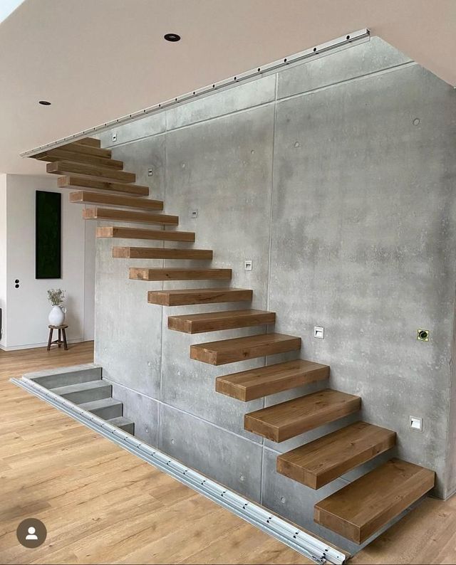Freitragende Holztreppe an einer Betonwand, heller Holzboden.