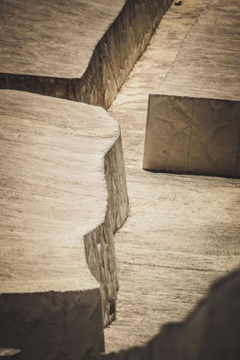 Betonkonstruktionen mit scharfen Kanten und tiefen vertikalen Einschnitten, die im natürlichen Licht Schatten werfen.