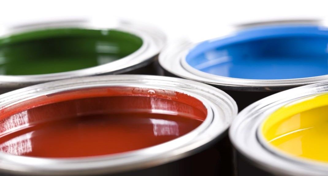 Four cans of paint of different colors  and paint finish are stacked on top of each other.