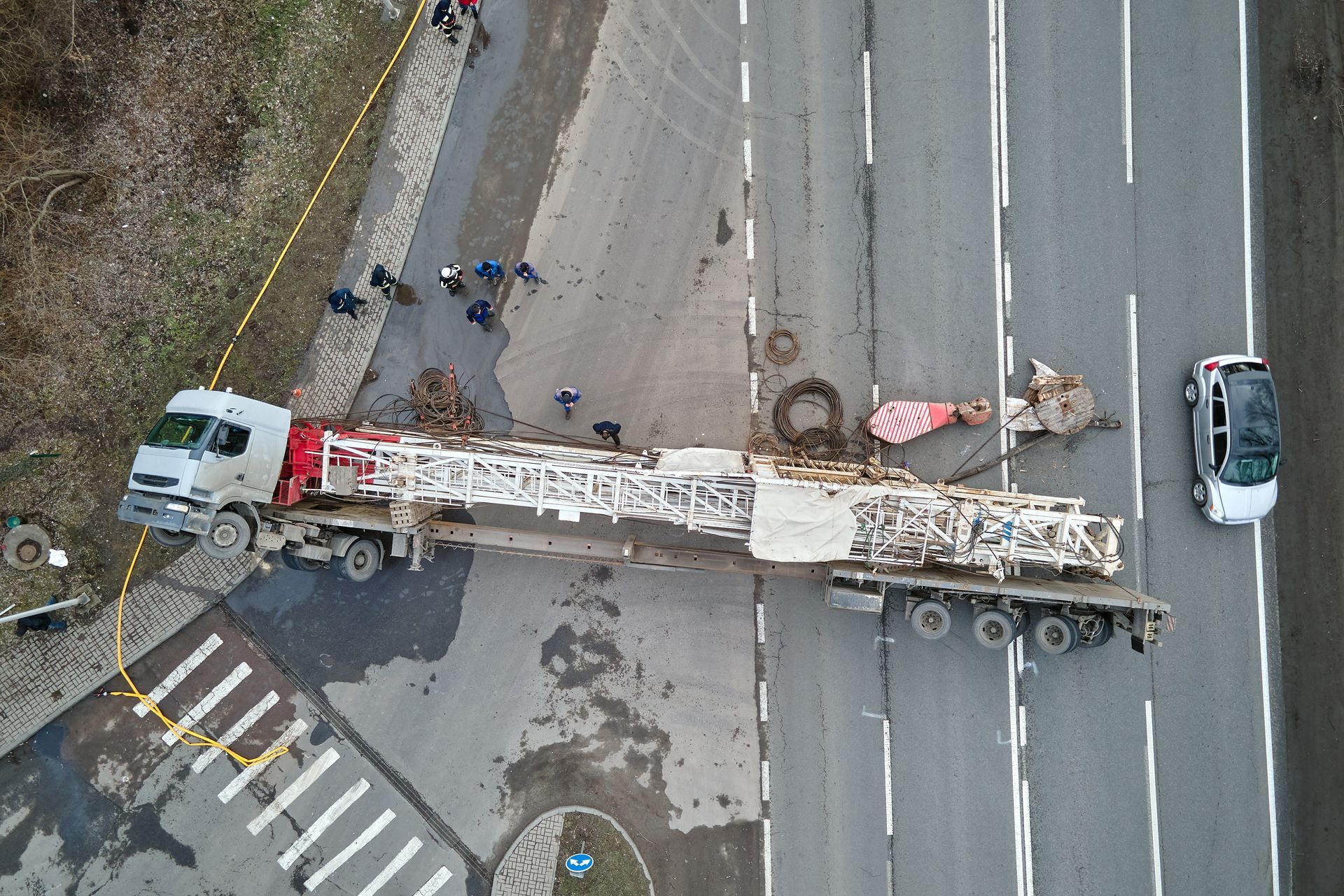 Aerial view of a truck carrying debris blocked across a multi-lane road, with workers nearby.