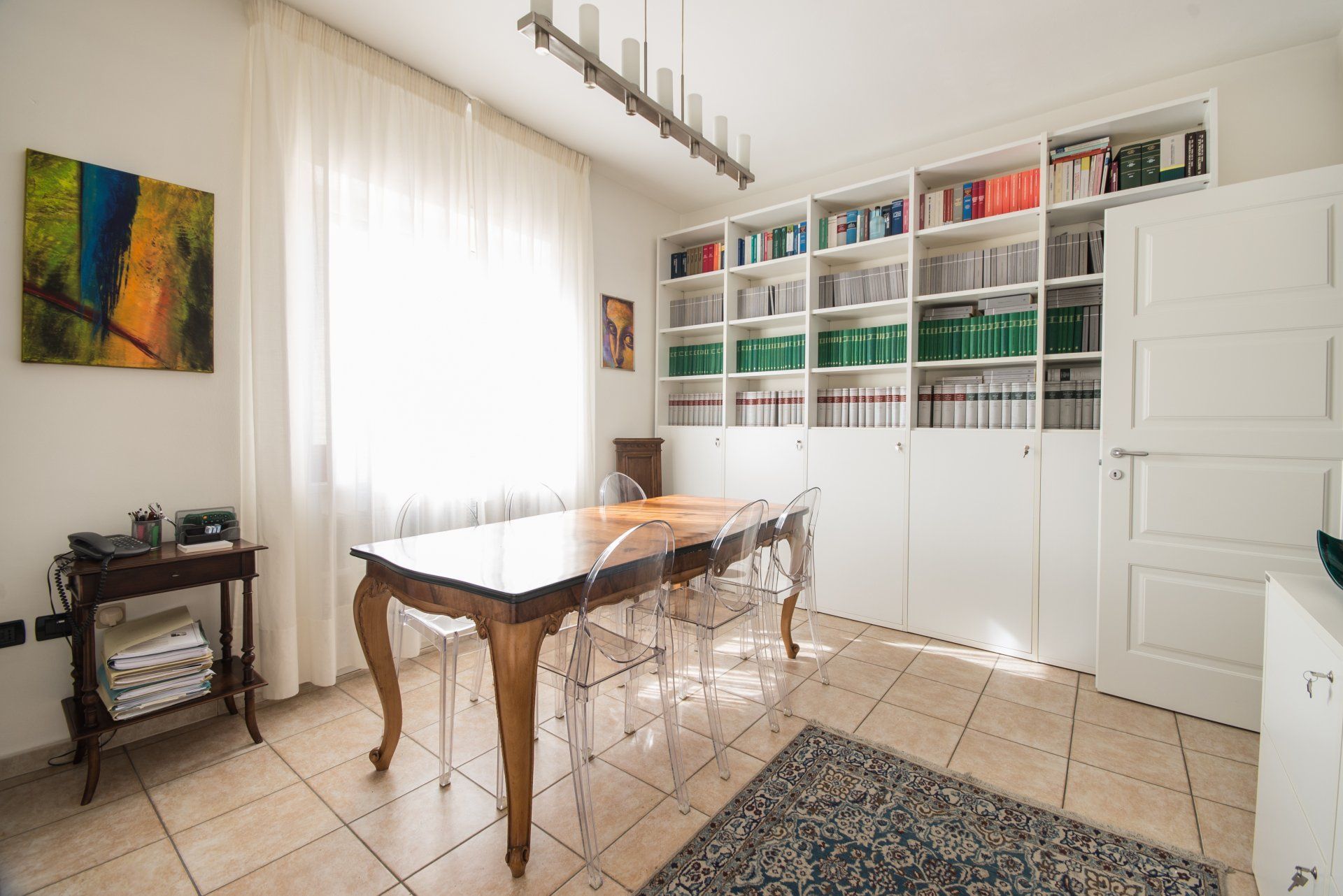 Una sala da pranzo con un tavolo, delle sedie e una libreria piena di libri.