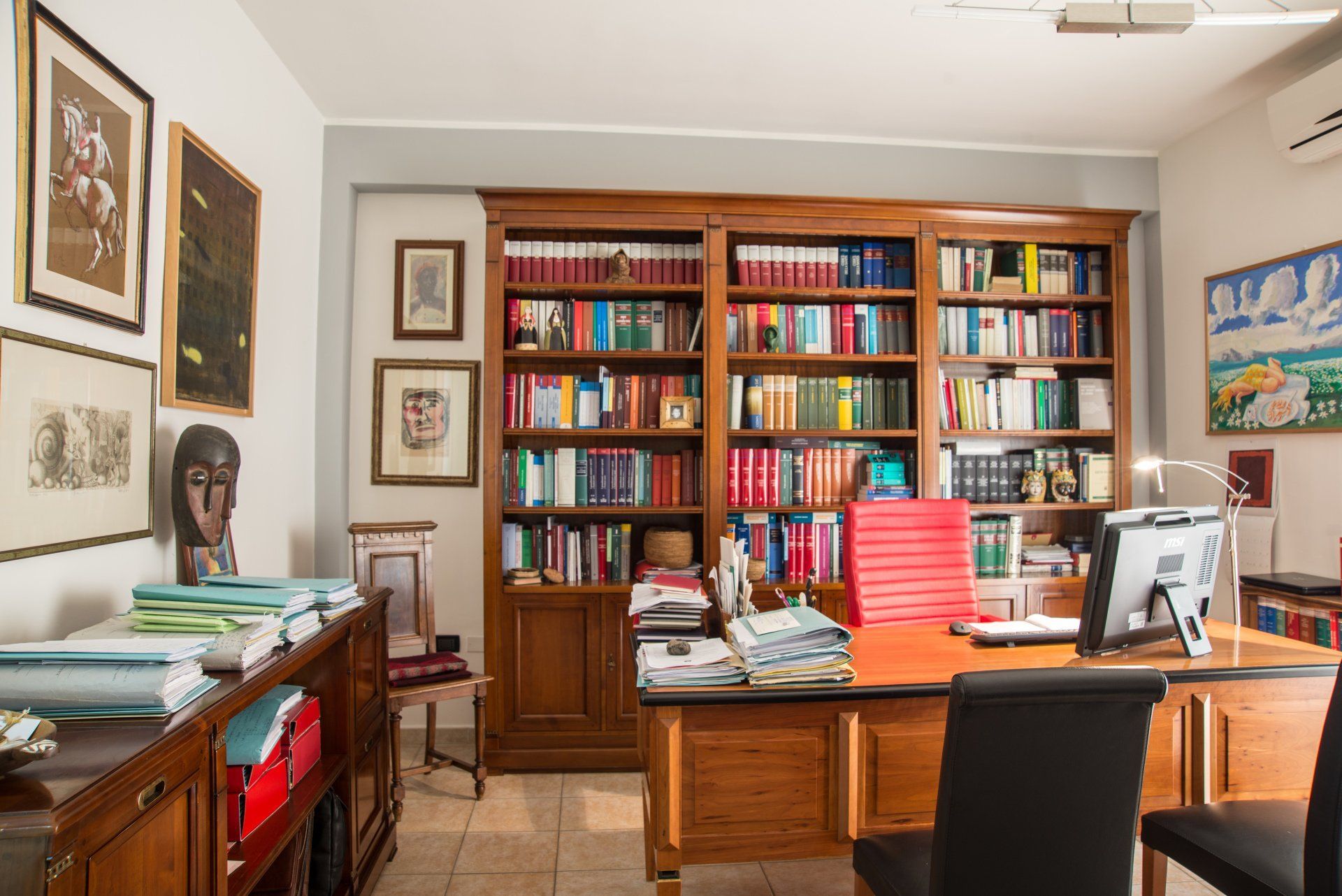 Una stanza con una scrivania, sedie, librerie e un computer.